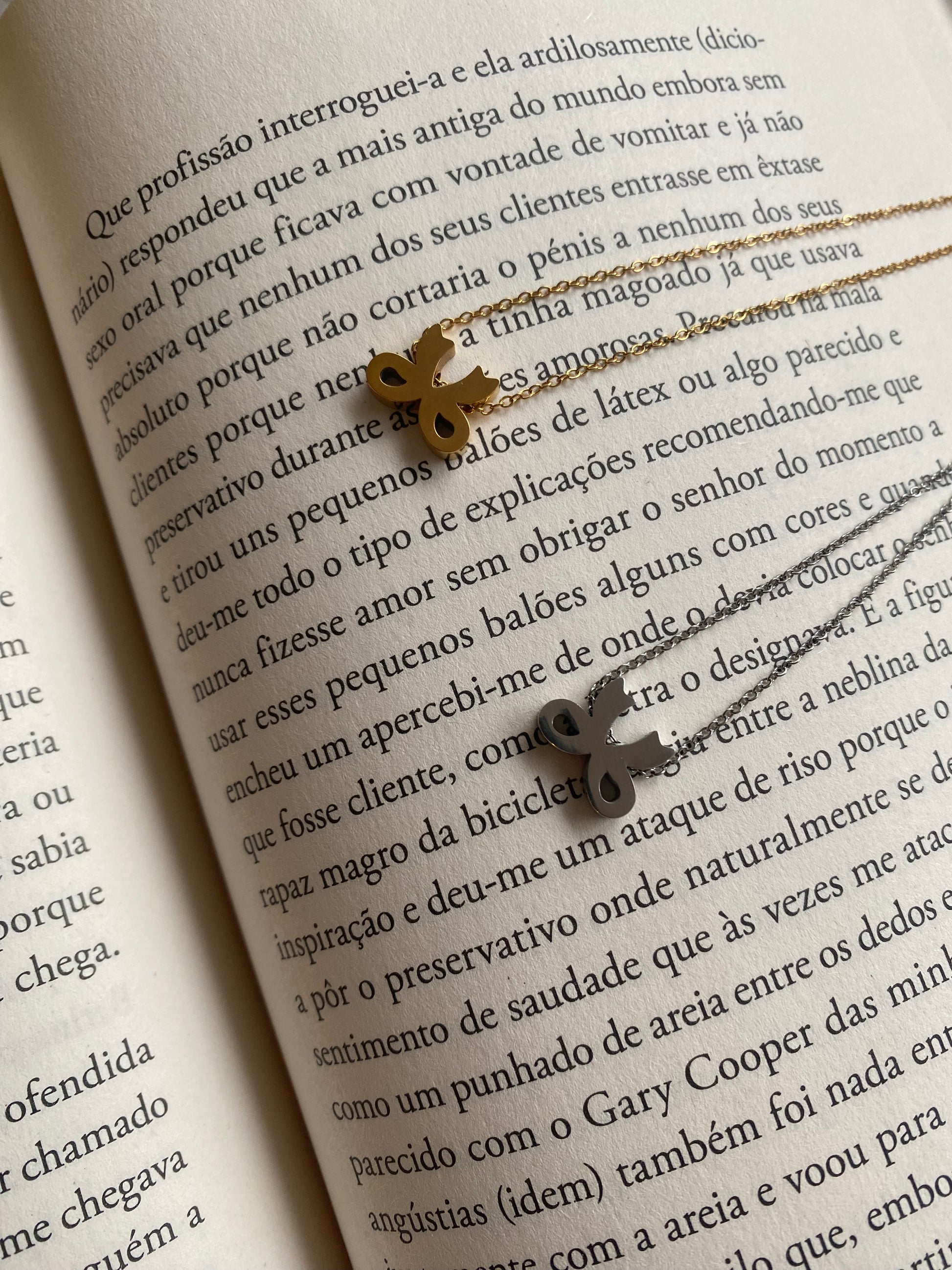 Colar simples com um pendente em forma de laço, em dourado ou prateado.