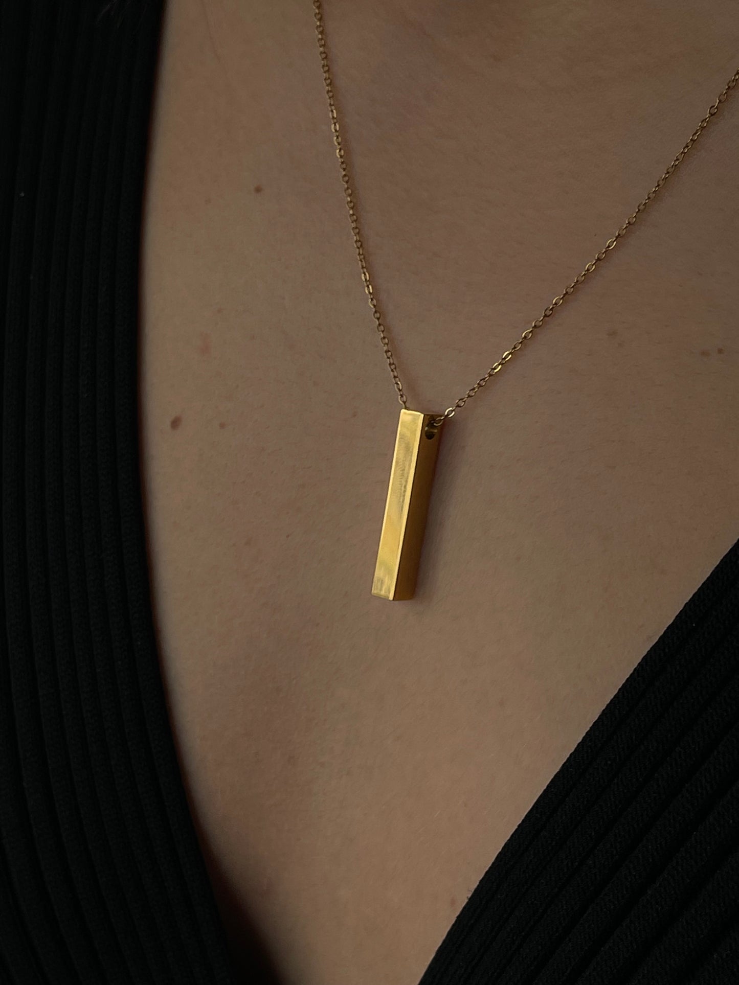 Colar dourado, simples e elegante, com um pendente retangular.